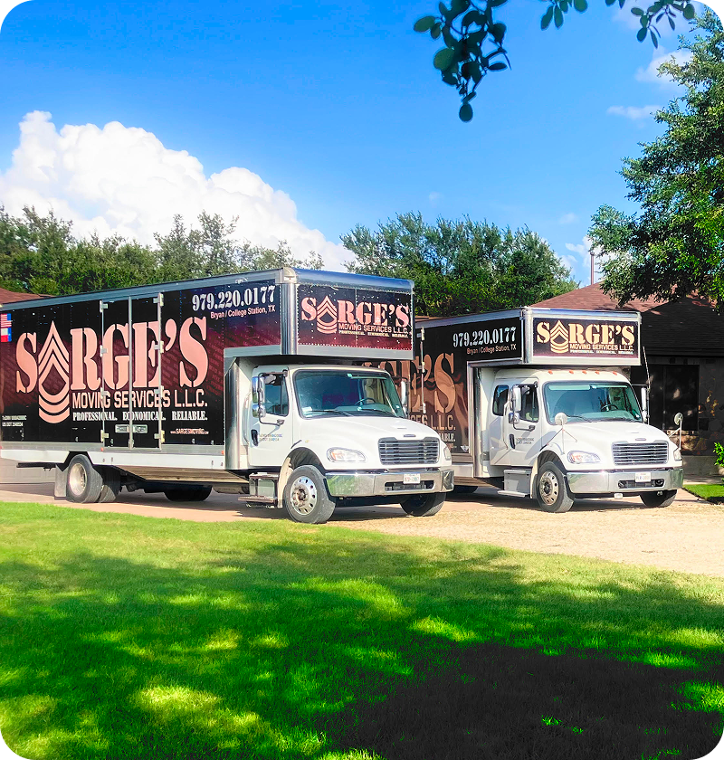 Two moving trucks parked on grass.