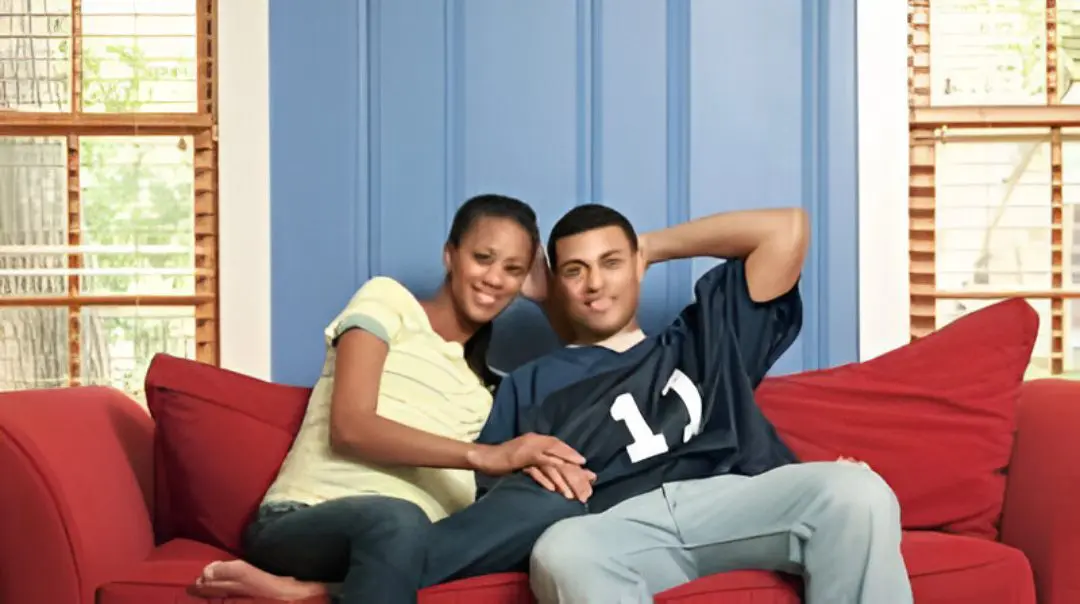 Couple sitting on a red couch, smiling.