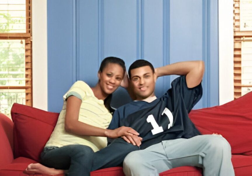 Couple sitting on a red couch, smiling.