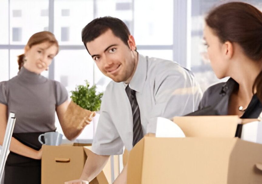Office workers packing boxes, smiling, moving day.